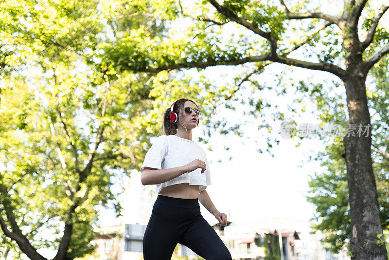 在城市里慢跑的年轻女性的肖像。(şehirde koşan kadın)一个阳光明媚的日子，一个金发美女在公园慢跑